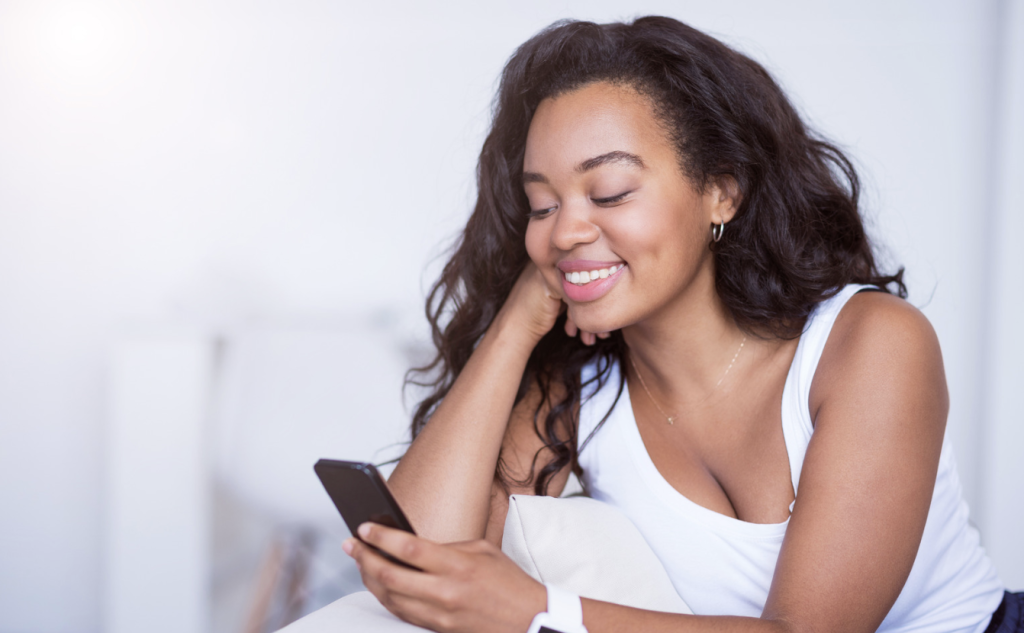 woman smiling at phone while she is using video dating app