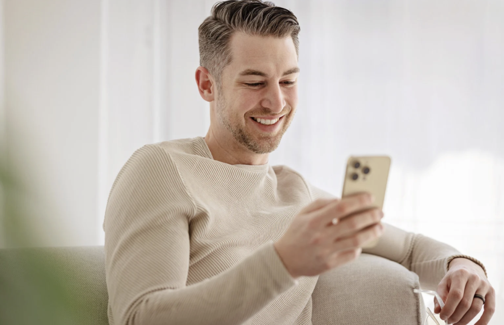 man smiling at phone while on a video chat with a woman he mat on groove app, best dating app in 2026